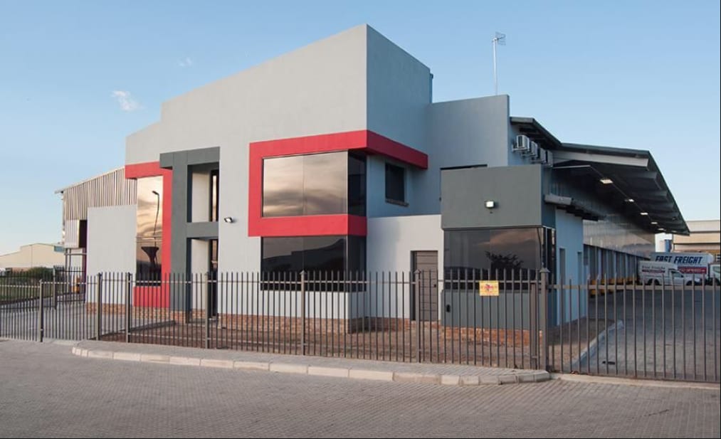 Completed commercial office block and warehouse facility with red banding and glazed corner in Harare